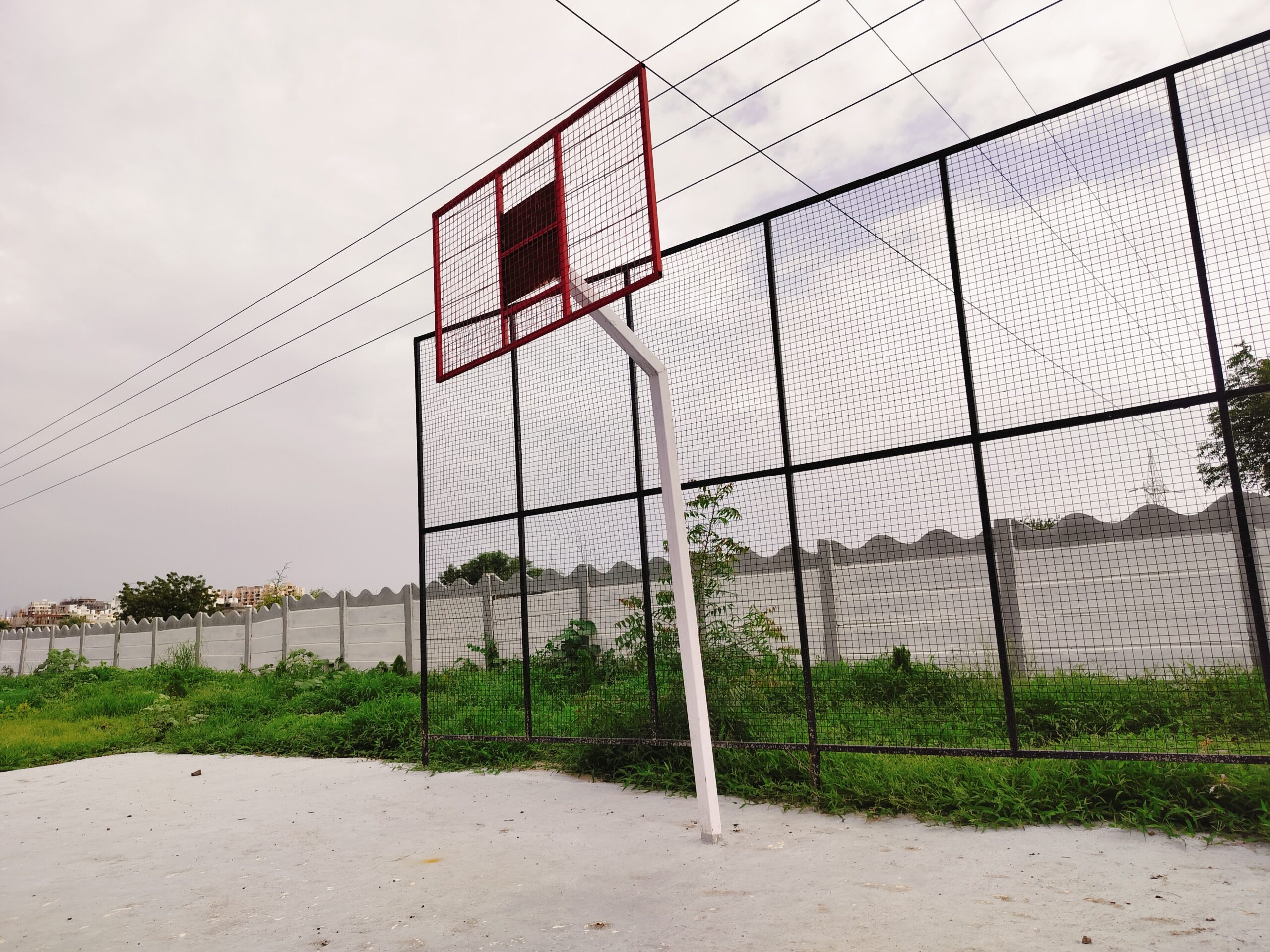 This image shows an open plot with a basketball court. The plot is located at Venkateshwara City in Vasant Vihar, Solapur, India. The basketball court is a great place for kids and adults to play basketball. The plot is also surrounded by trees and other vegetation, which provides shade and privacy. This image is a good representation of the kind of amenities that are available at Venkateshwara City.